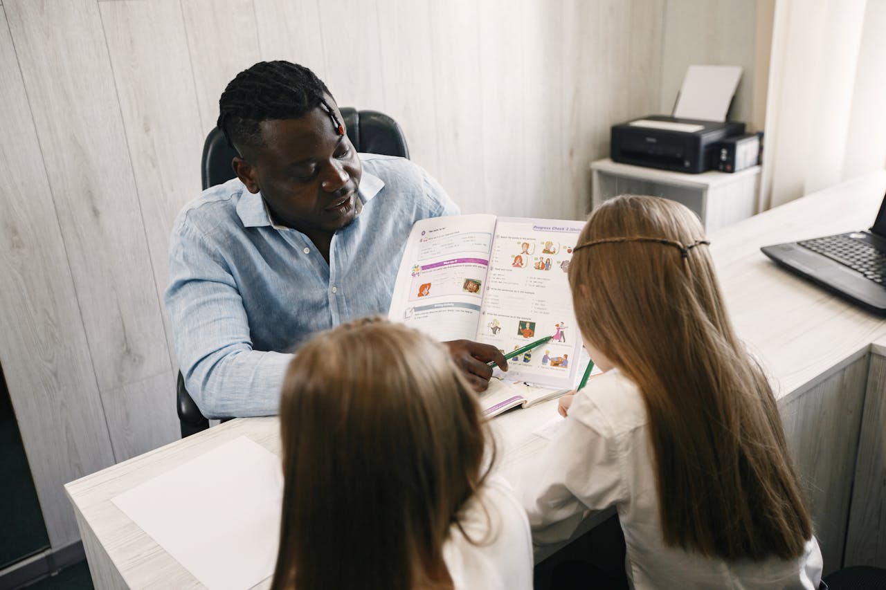 A teacher guiding students through a textbook during a home schooling session.
